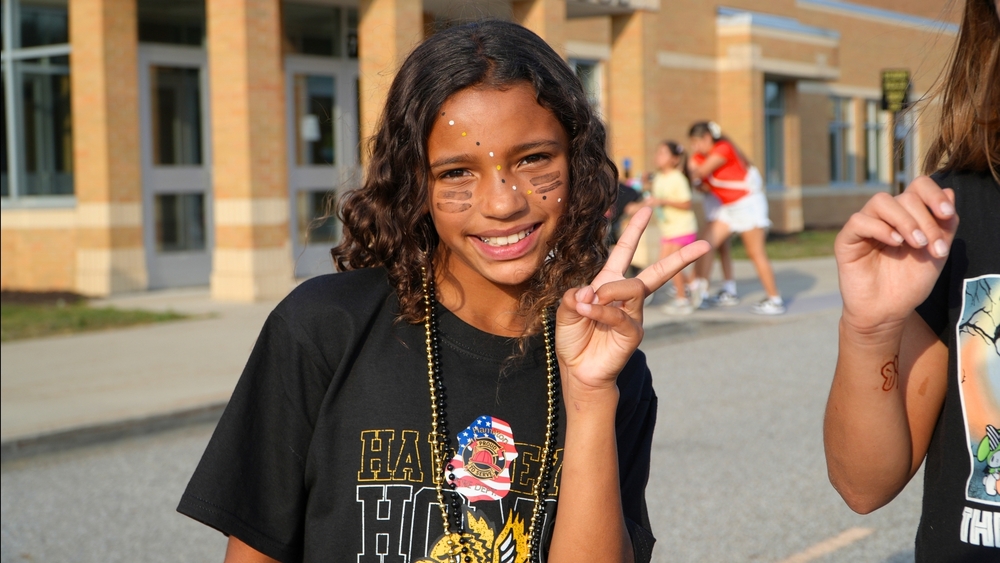 A female smiles with a peace sign and black shirt.