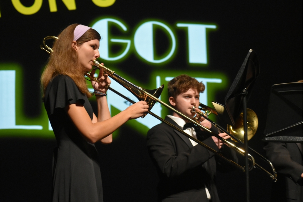 A male and female student play an instrument on a stage.