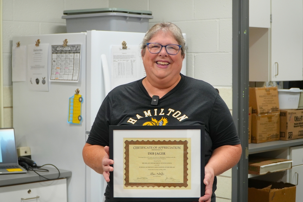 Deb Jager smiles and holds a certificate of appreciation.