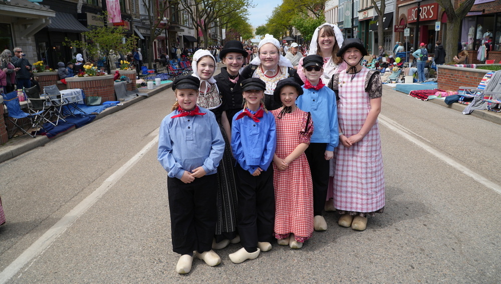 A group of student Dutch Dancers smile in the street.