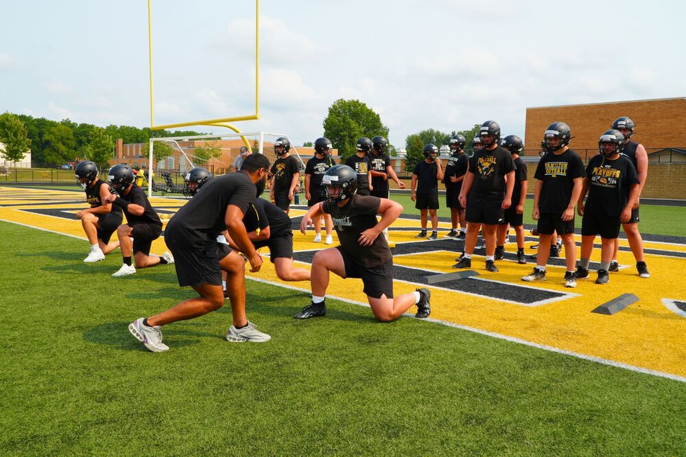 Football players on a football field with a coach.