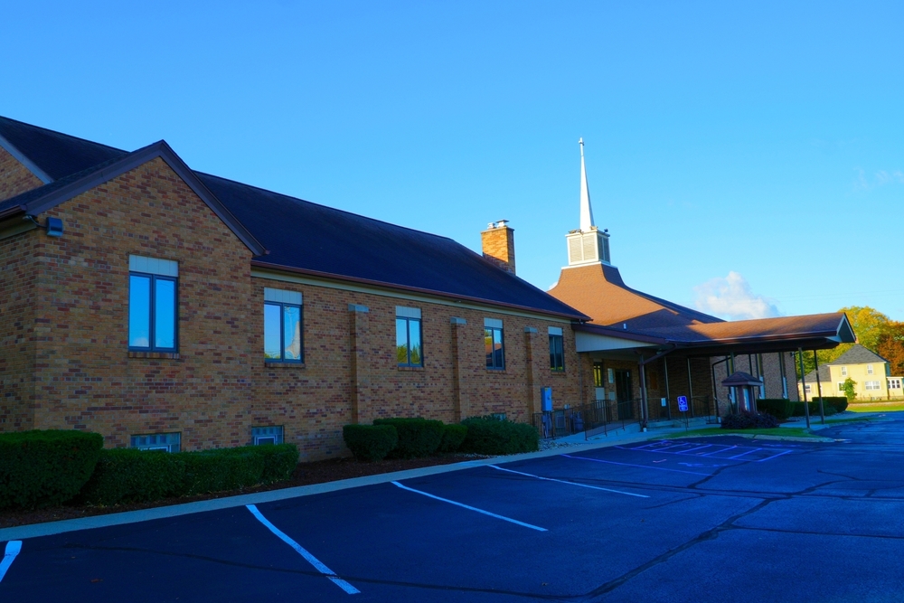 A brick building with windows and a parking lot on a sunny day.