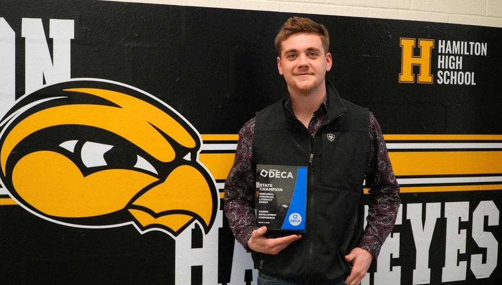 A male student smiles with a DECA award.