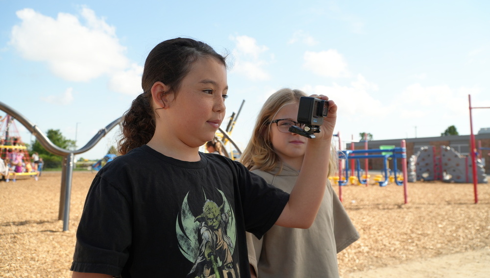 A student holds a GoPro camera while smiling.