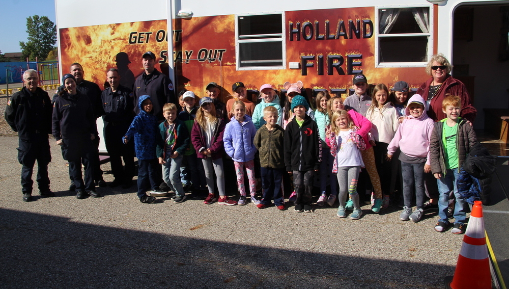 Students stand in front of the Holland fire trailer with members of the Graafschaap fire department.