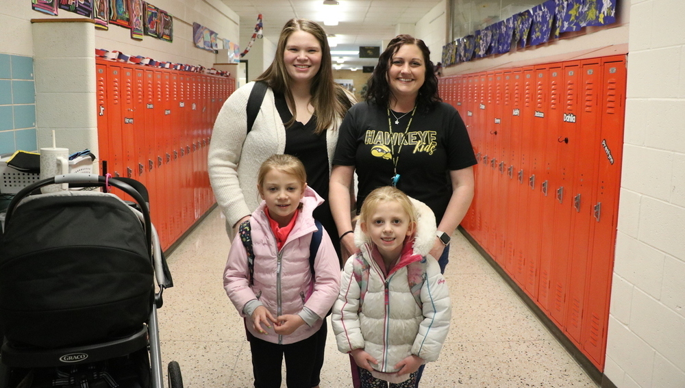 A Hamilton Community Schools staff member with a mother and two female kids in a hallway.