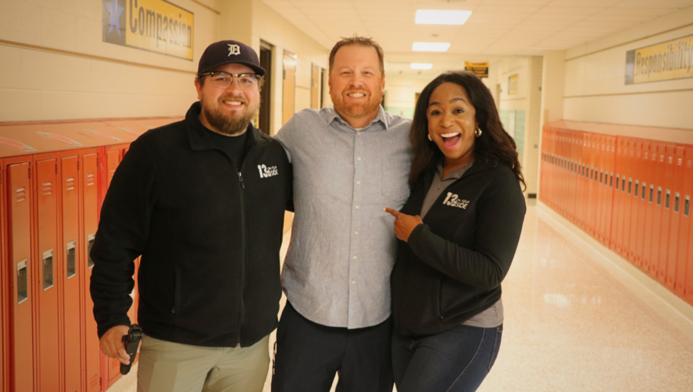 Mr. S smiles in a hallway with two WZZM staff members.