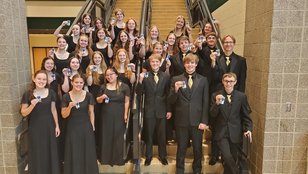 Hamilton choir students hold up medals from festival.