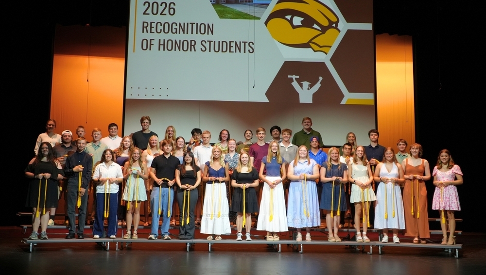 A group of students smile with their honors chords.