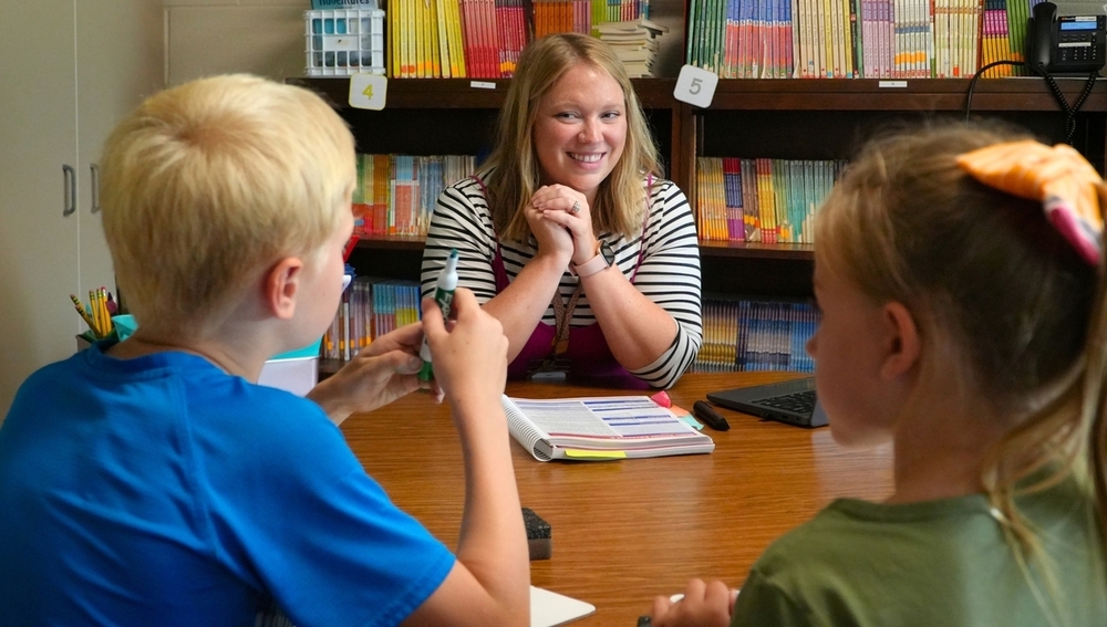 Kate Ojeda smiles at students while working in a small group.