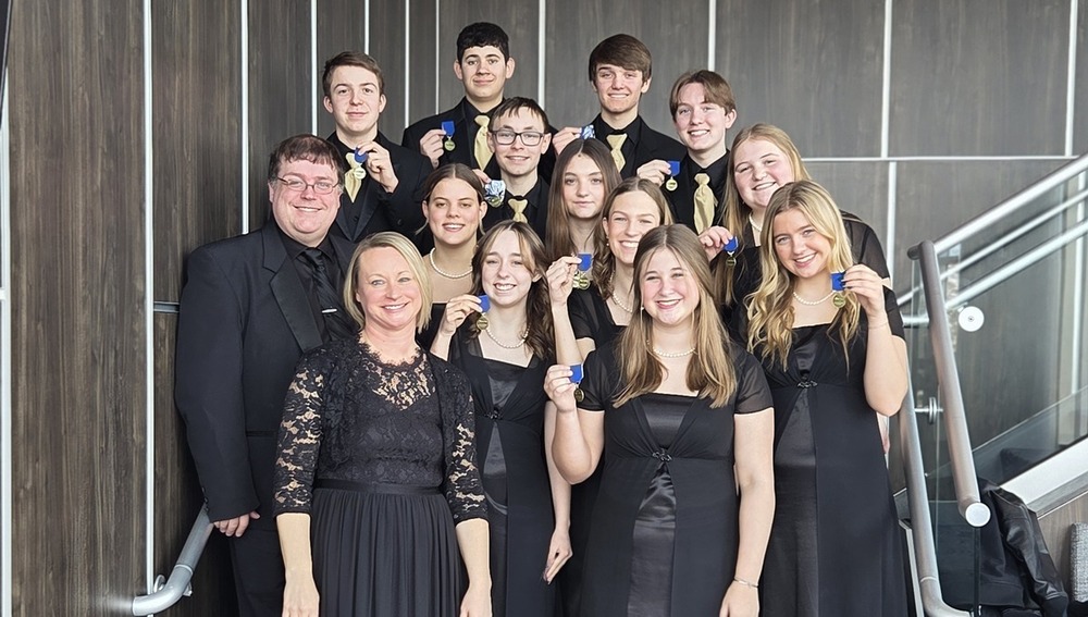 A group of students smile and hold up medals.