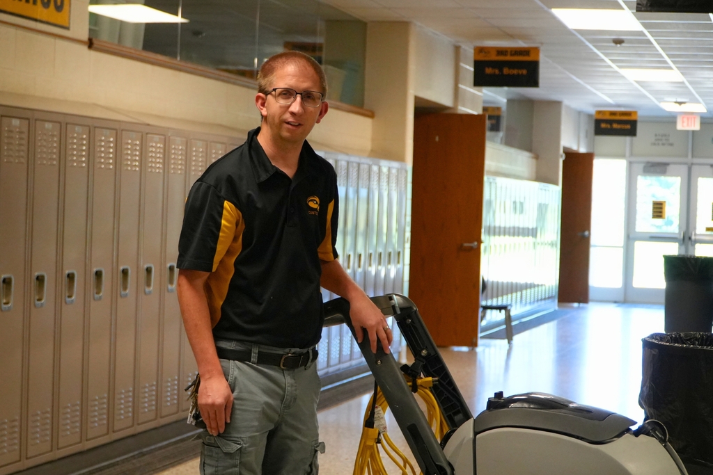 A male staff member smiles in a hallway.