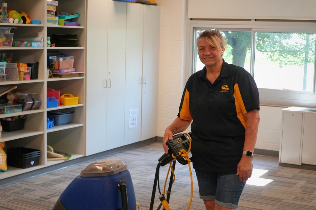 A female staff member smiles in a classroom.