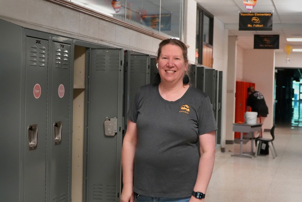 A female staff member smiles by open lockers.
