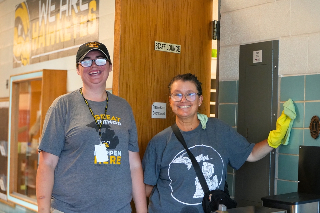 Two female staff members smile in a hallway.