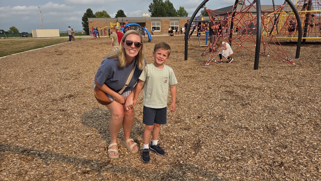 A parent and son smile on the playground.