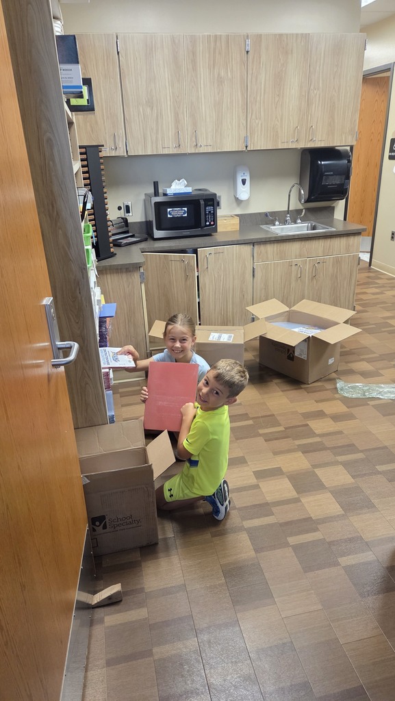 A male and female student smile while unpacking boxes.