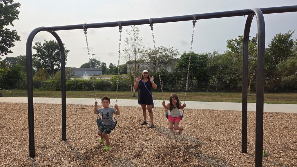 A parent with a male and female student on swings.