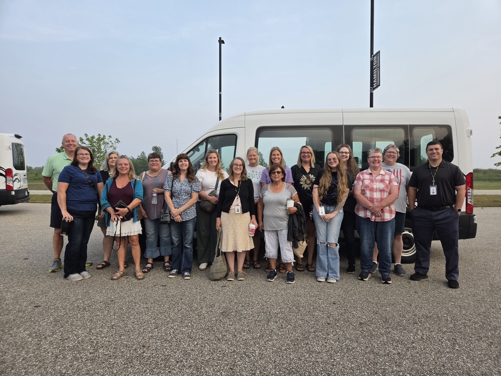 A group of adults smile in front of a van.