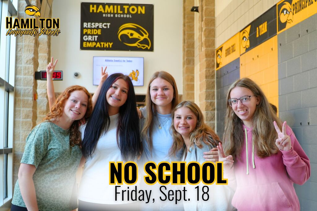 Five female high school students smile in a hallway.