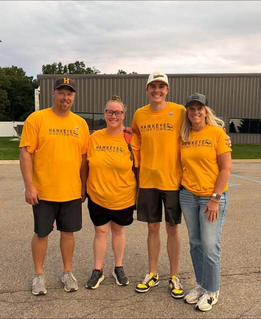Hawkeye Hometown Tailgate committee, four people smile in gold shirts.