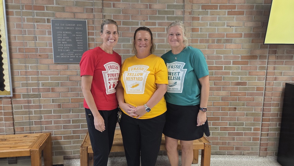 Three staff members dressed in red, yellow, and green shirts that are condiments. 