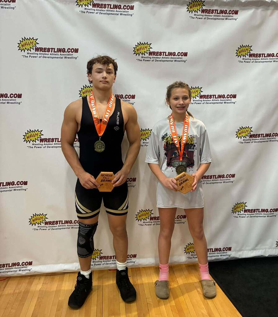 Two Hamilton wrestlers in front of a backdrop.