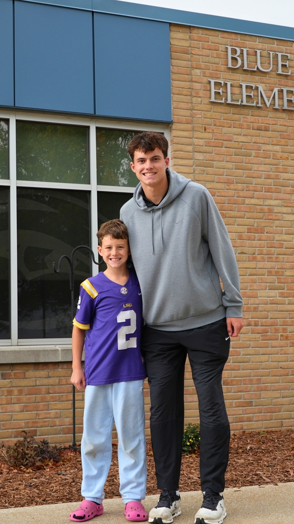 A football player smiles with his younger brother outside of Blue Star Elementary.