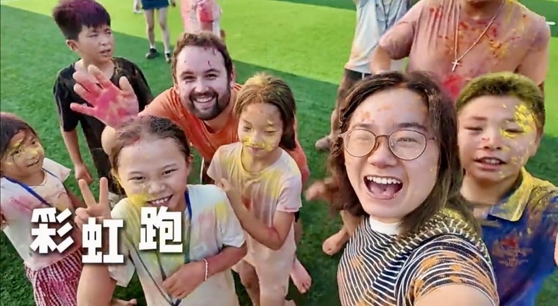 A group of students and two teachers smile with paint on their face.