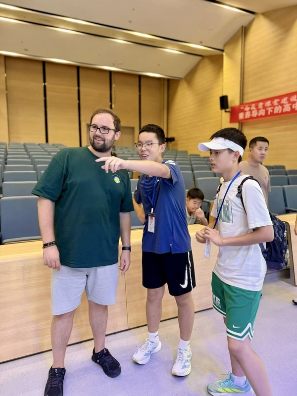 Two students point with a smiling male teacher looking on.