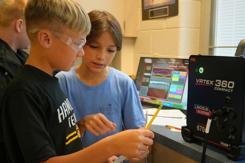 Two male students look at a piece of paper inside their learning lab.