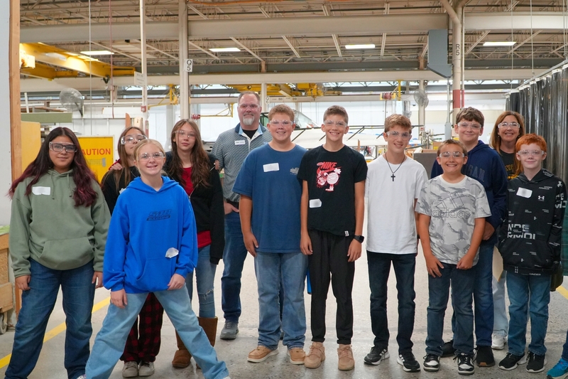 Students stand with a staff member from Tiara Yachts on the floor.