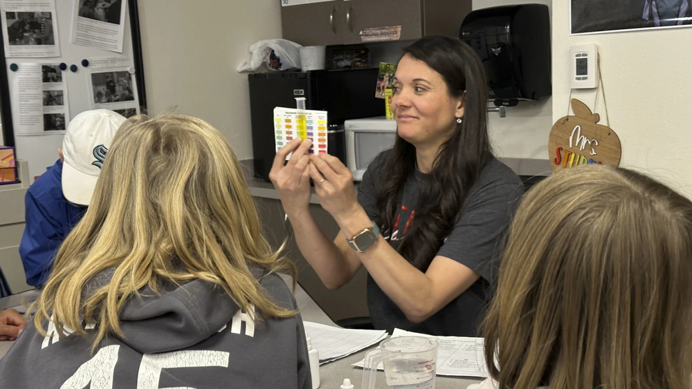 Ms. Stuber working with her 4th grade students to test PH levels in their trout tank