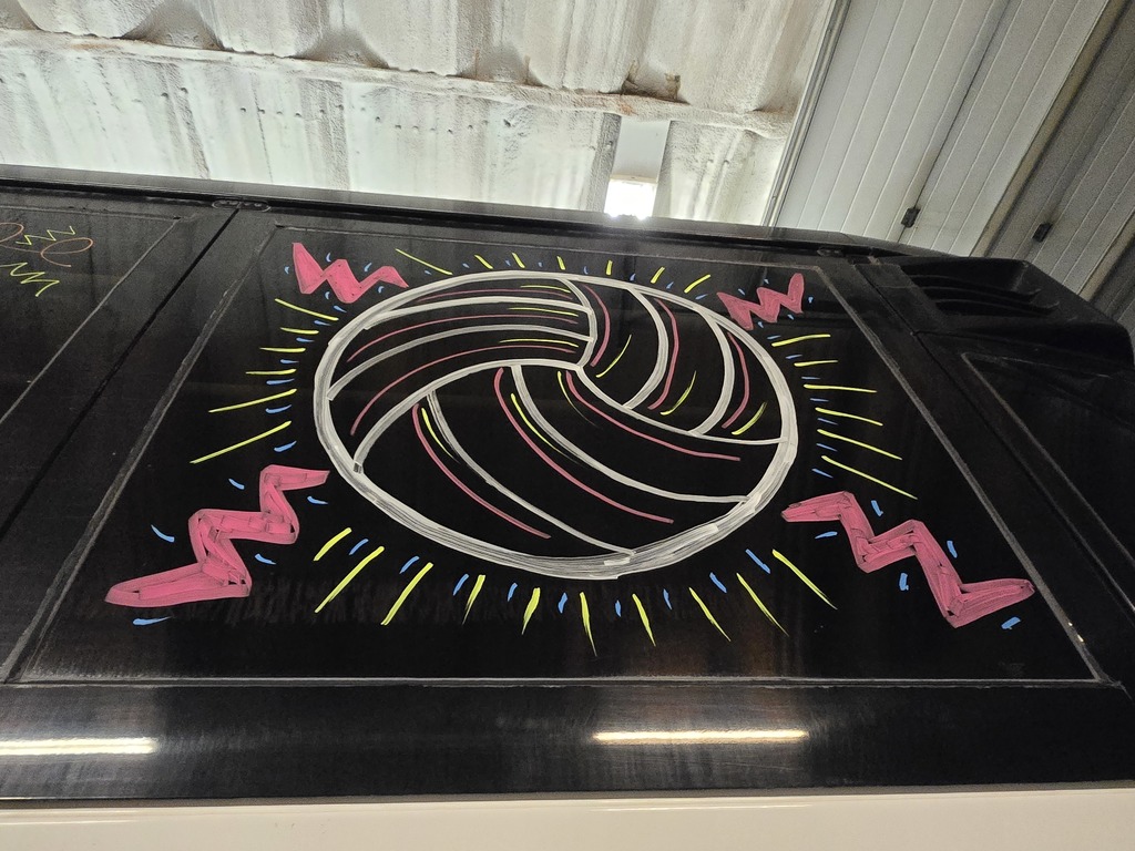 Photos of decorations on the bus windows for the high school volleyball bus that will taking the team to state. This window has a picture of a pink and white volleyball.