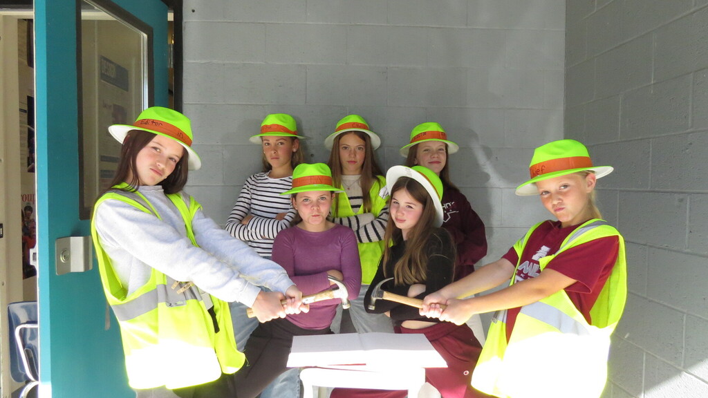 Hamilton Middle School yearbook students with hats and hammer posing with a sample of the yearbook