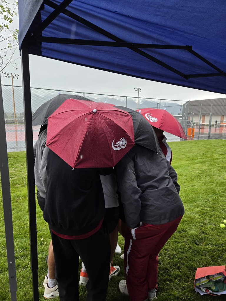 HHS Bronc tennis team huddled together in the rain during the divisional tournament