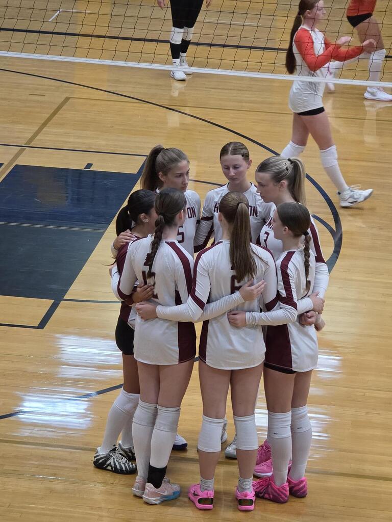hhs volleyball standing in a circle on the volleyball court