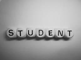 White blocks arranged in a row spell out the word “STUDENT.” The letters are printed in bold black font, and the blocks are placed on a smooth surface with a soft gray gradient background. The image has a simple, monochromatic style that emphasizes the word “STUDENT.”