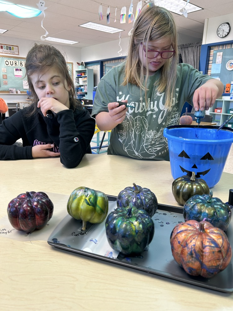 students painting pumpkins