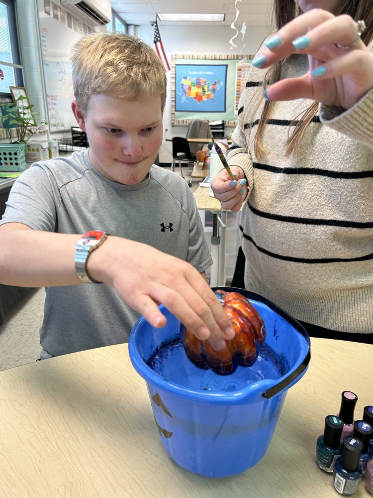 student painting pumpkins