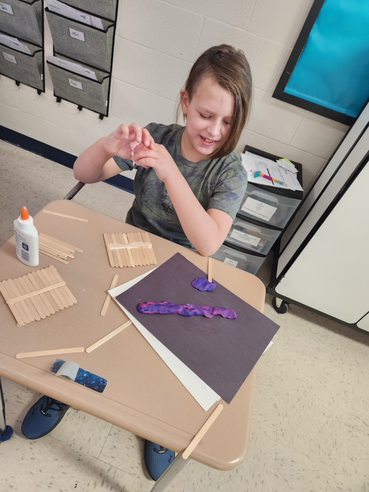 student building with popsicle sticks, glue, and clay