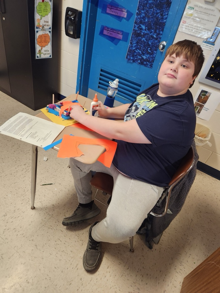 student building with popsicle sticks, glue, and clay