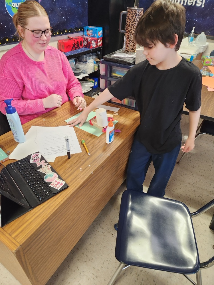 student building with popsicle sticks, glue, and clay