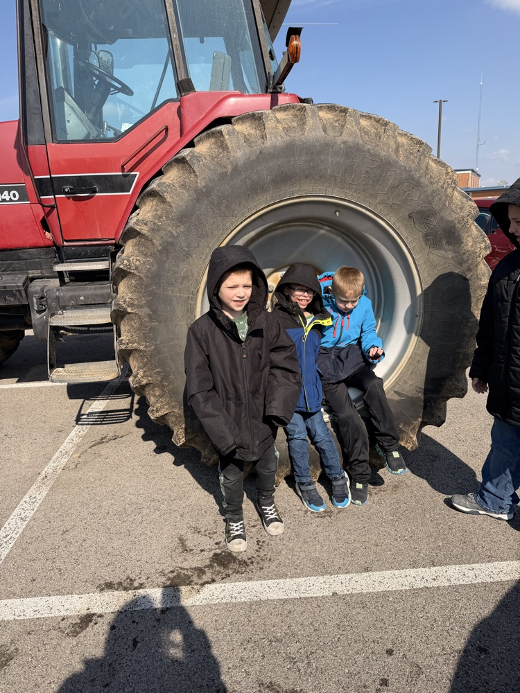 students sitting in front of tractor tire