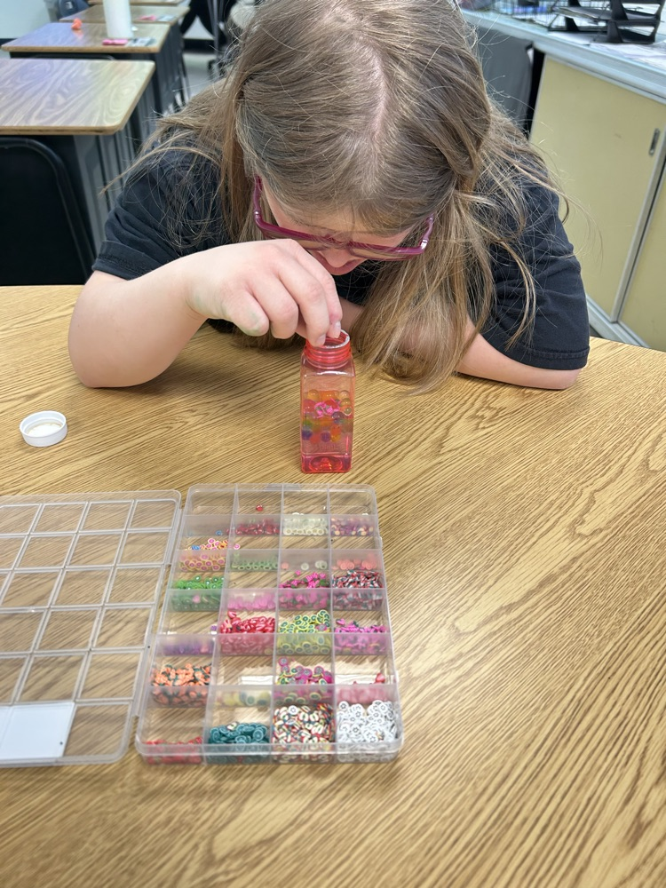 student putting beads in jar