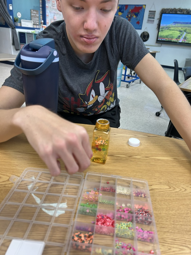 student putting beads in jar