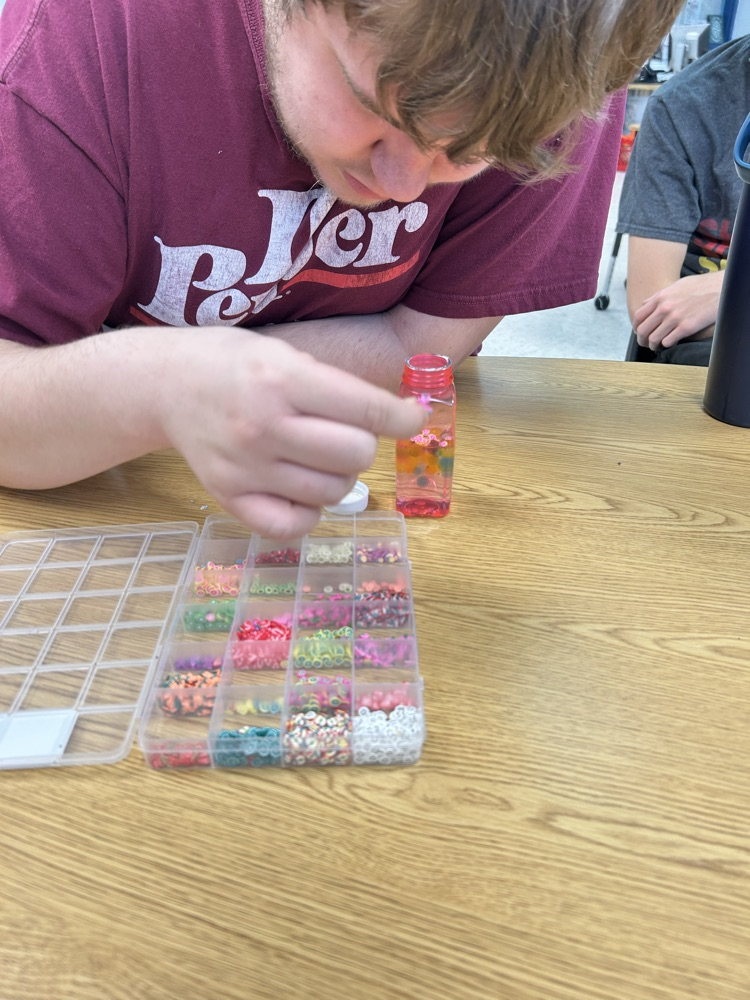 student putting beads in jar
