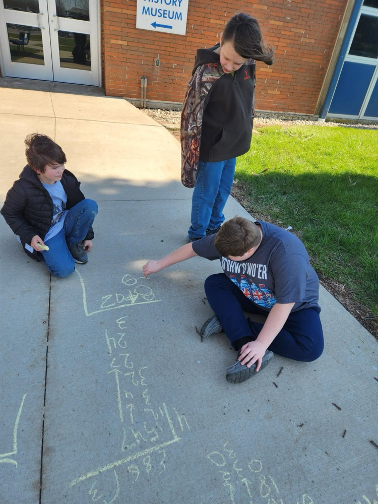 students outside practicing math using sidewalk chalk
