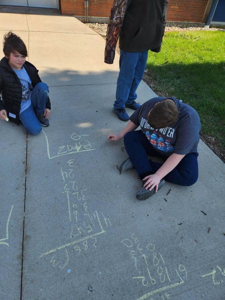 students outside practicing math using sidewalk chalk