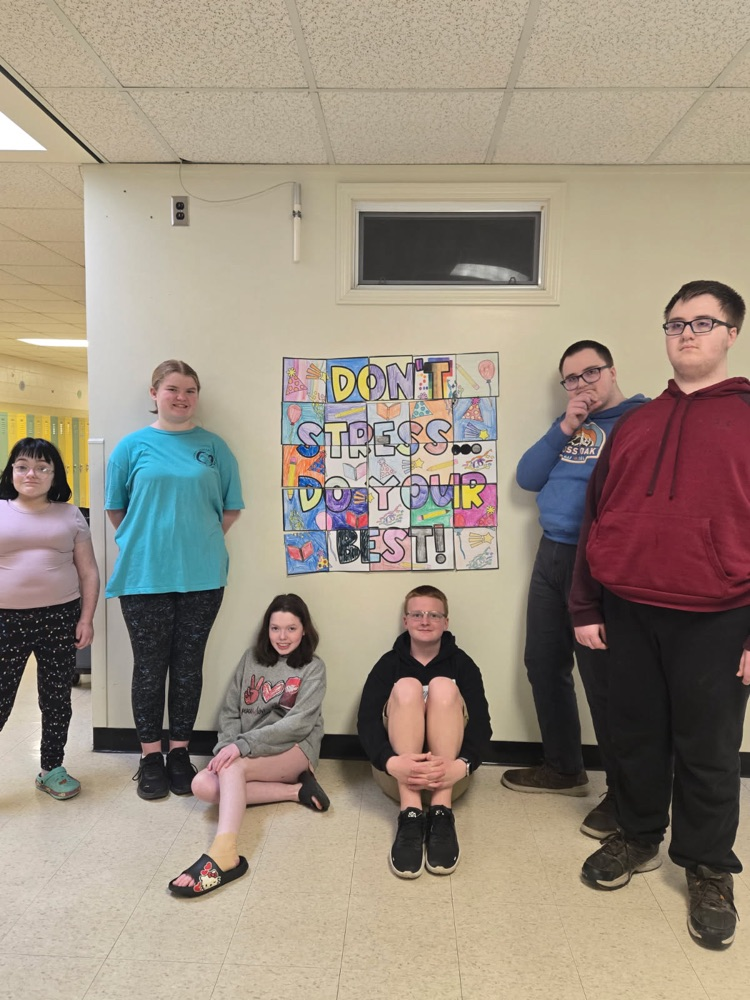 students in front of “don’t stress do your best” poster 